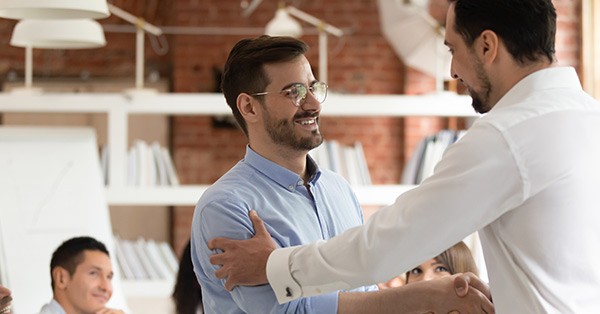 Man shaking hands with another man and his hand on his arm