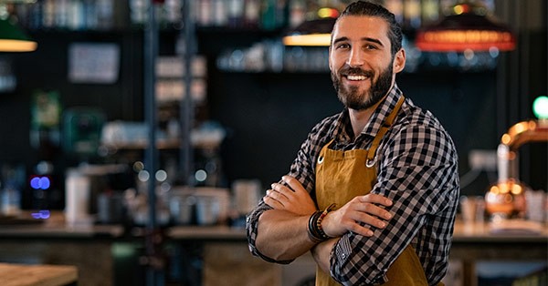 Small business man wearing apron with arms crossed