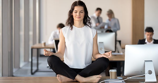 Woman doing yoga on desk at work