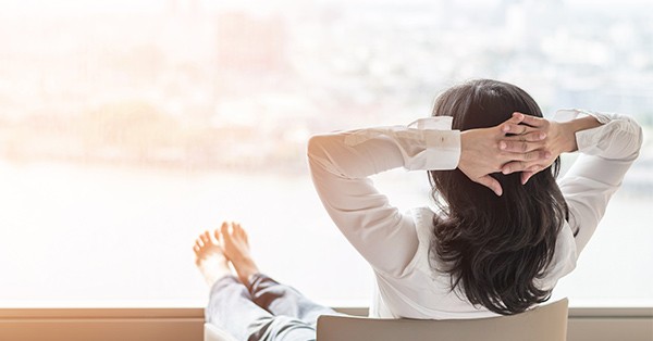 Woman with hands behind head relaxing at work