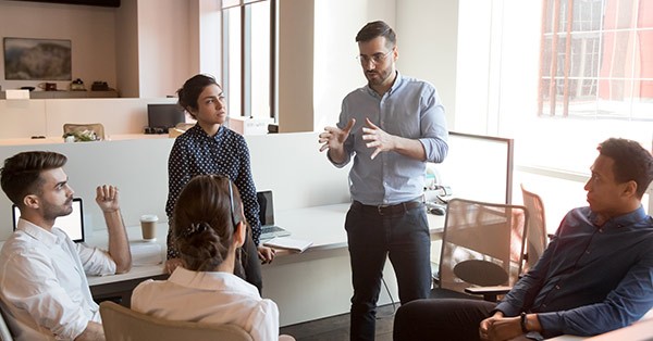 Employees having a meeting with man standing