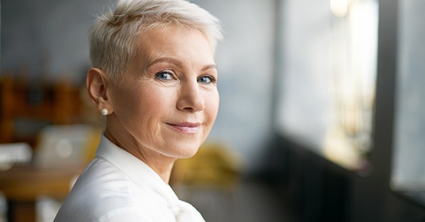 Older woman in professional clothes in an office building looking at the camera.
